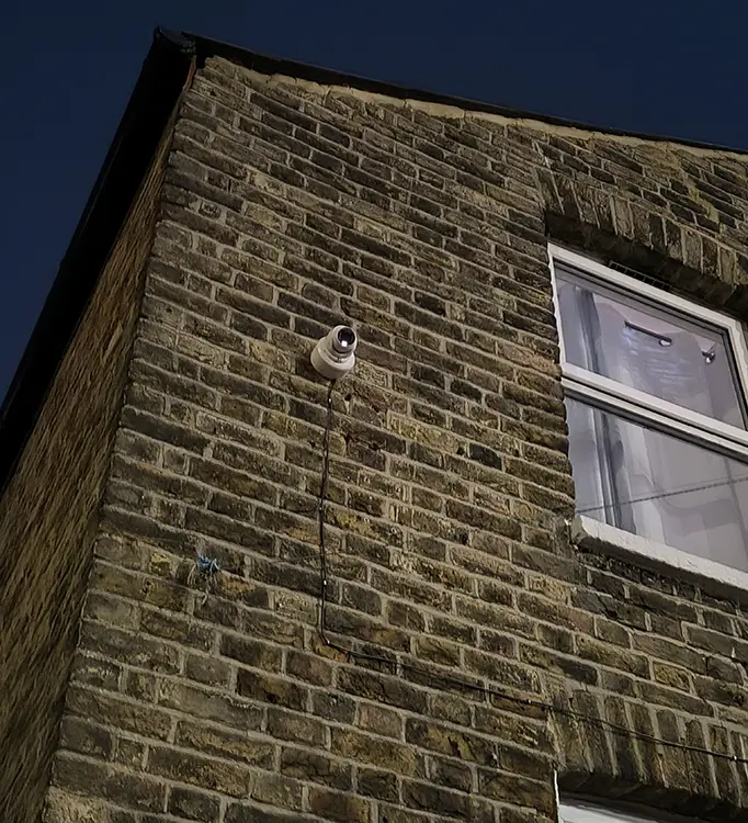Outdoor CCTV security camera mounted on corner of Victorian brick wall at residential property in Lambeth, South London