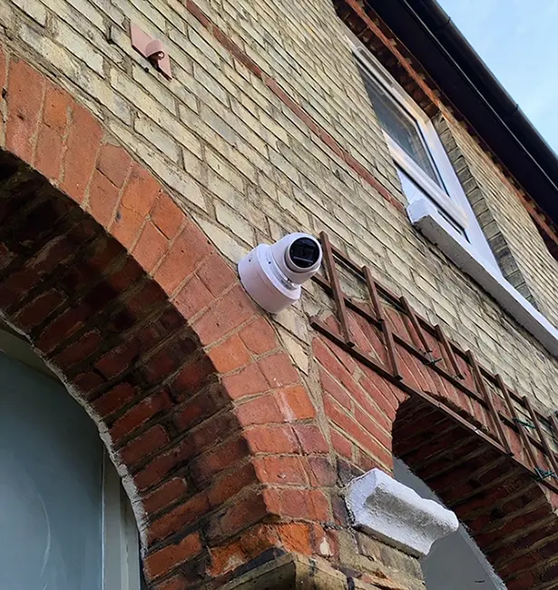 CCTV bullet camera installed on brick arch of commercial building in Twickenham TW1