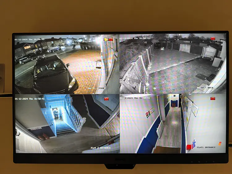 CCTV monitor showing 4-channel live view of block of flats entrances and car park in Mitcham CR4