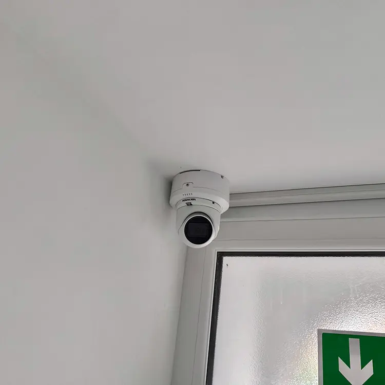 Dome CCTV camera installed above emergency exit sign in commercial property in Twickenham TW1