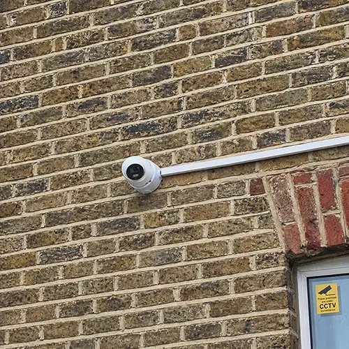 Exterior CCTV camera installed on brick wall with CCTV surveillance sign in Twickenham TW1