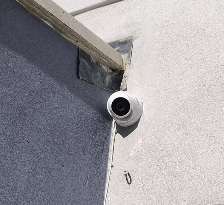 Outdoor dome CCTV camera mounted on exterior wall under roof eave at residential property in Dulwich SE22