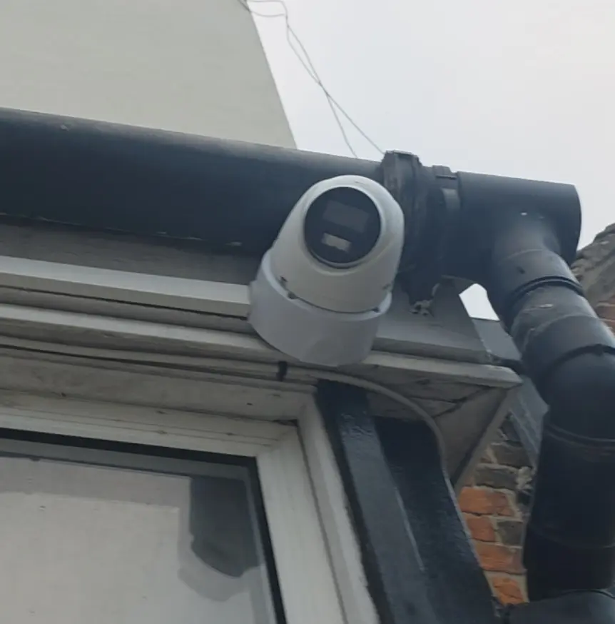 Outdoor dome CCTV camera installed under roofline on exterior wall of commercial premises in Mitcham CR4